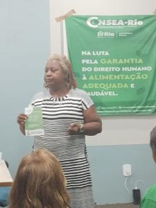 Sheila, durante atividade no CONSEA, apresentando material informativo do Fórum TBRJ